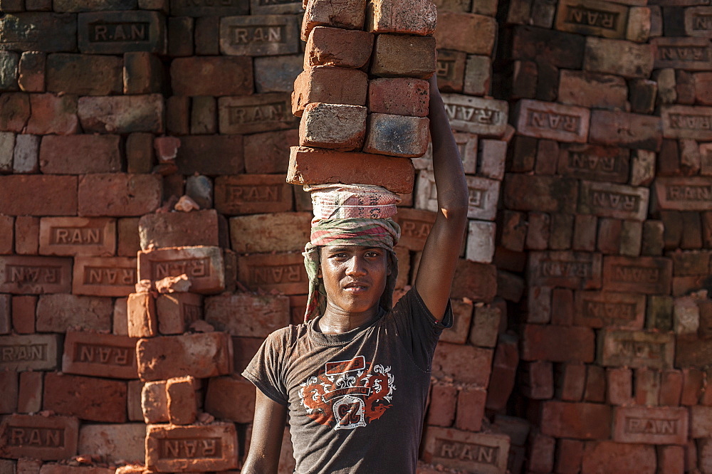 A young man carries up to 50 kilos of bricks by balancing them on his head, brick factory in Chittagong Hill Tracts, Bangladesh, Asia