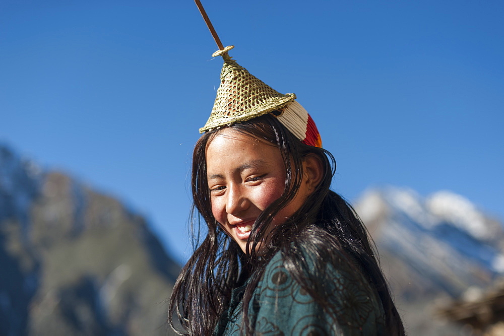 A Layap girl wearing a traditional hat smiles for the camera in the remote village of Laya, Bhutan, Asia