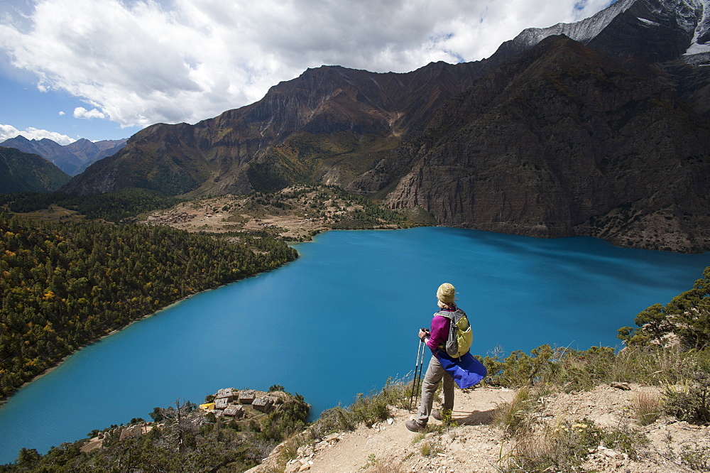 A trekker stands above the turquoise blue Phoksundo Lake in the Dolpa region, Himalayas, Nepal, Asia