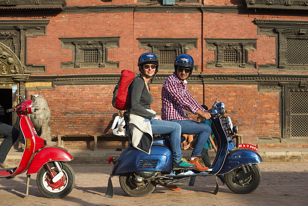 A tourist on a scooter outside a Newari building in Patan in Kathmandu, Nepal, Asia