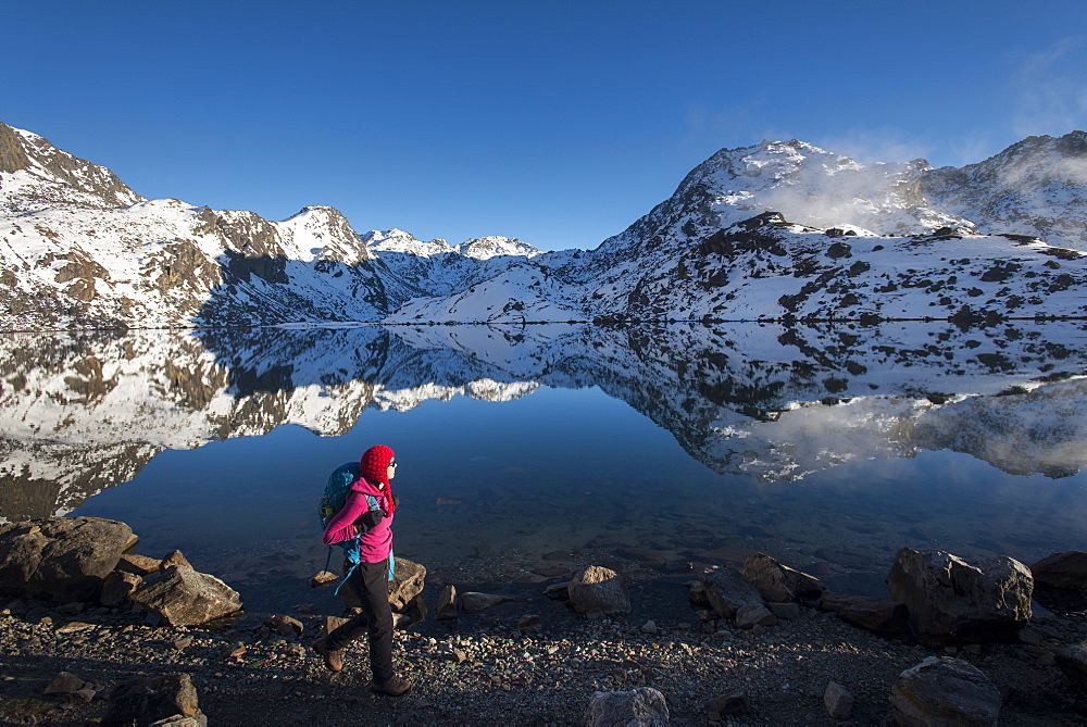 A woman walks past the holy lake of Gosainkund in the Langtang region, Himalayas, Nepal, Asia