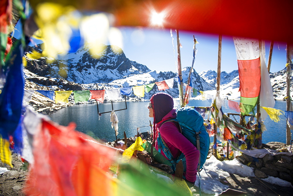 A trekker stands among prayer flags beside the holy lakes at Gosainkund in the Langtang region, Himalayas, Nepal, Asia