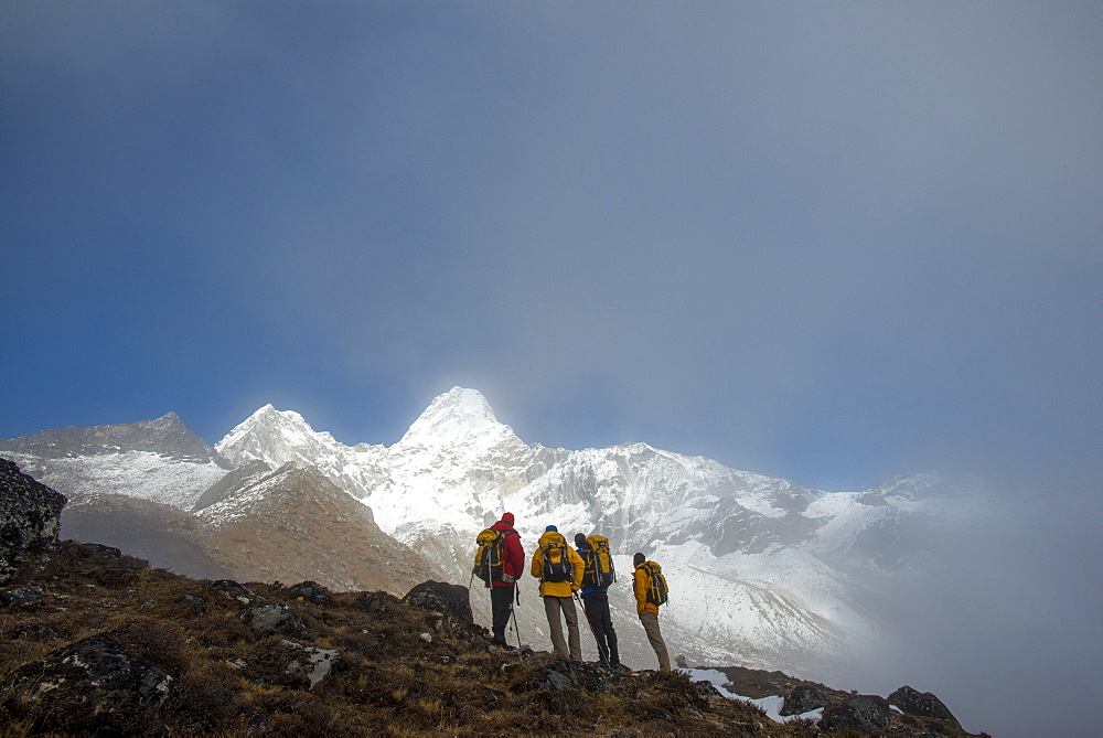 A team of four climbers make their way to Ama Dablam Base Camp, the 6856m peak seen in the distance, Khumbu Region, Himalayas, Nepal, Asia