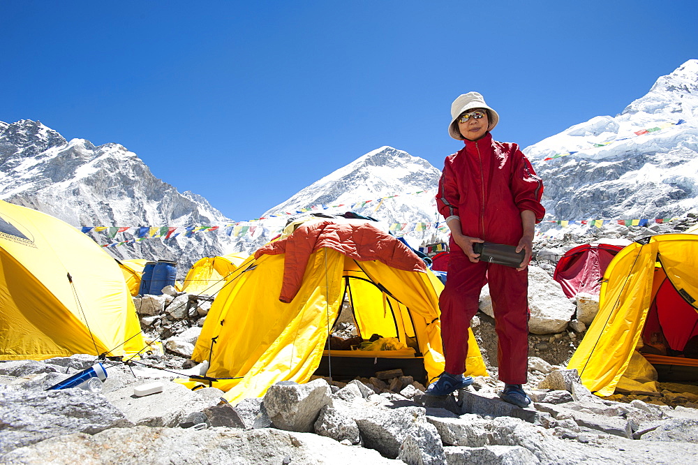 A woman stands by her tent shortly after climbing Everest, Khumbu Region, Himalayas, Nepal, Asia