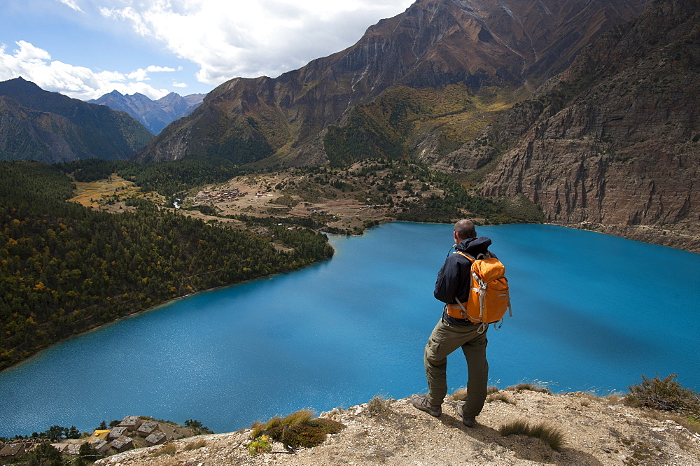 A trekker looks out at the turquoise blue Phoksundo Lake, Dolpa Region, Himalayas, Nepal, Asia