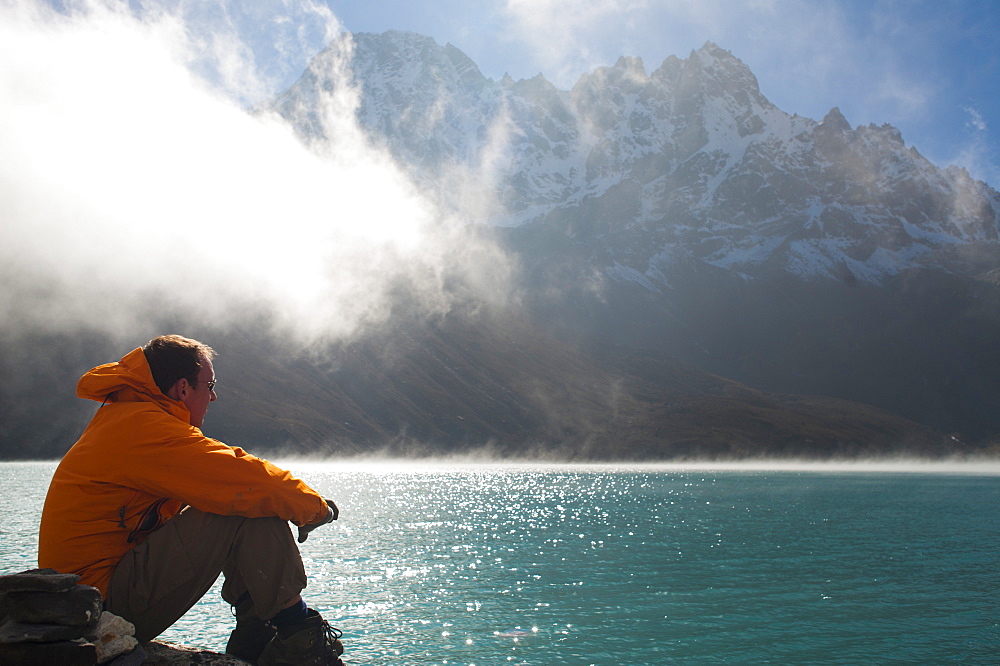 A trekker in the Everest region looks out over Gokyo Lake, Khumbu Region, Nepal, Asia