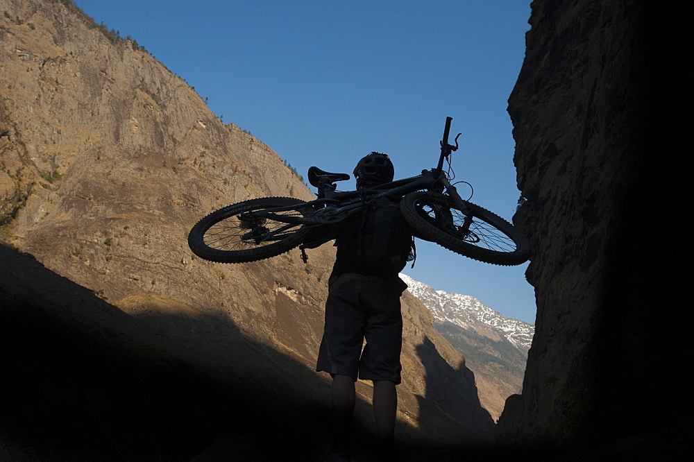 A mountain biker carries his bike into the Himalayas, Nepal, Asia