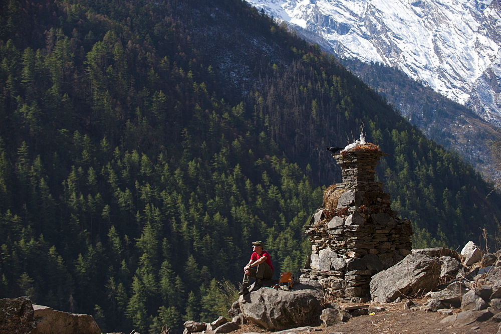 A trekker stops by a chorten in the Tsum Valley, Nepal, Asia