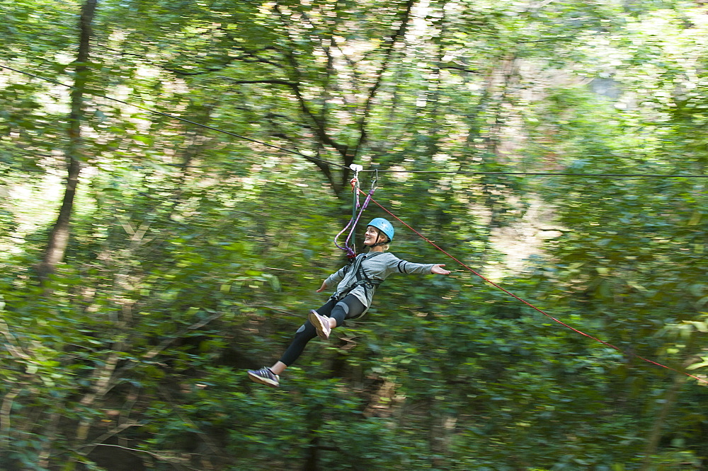 A girl holds her arms out while on a zip line, Nepal, Asia