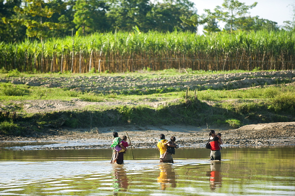 Women cross a river carrying their children in their arms, Chittagong Hill Tracts, Bangladesh, Asia