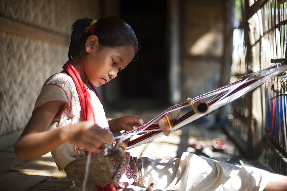 A little girl learns the skill of weaving on a handloom, Chittagong Hill Tracts, Bangladesh, Asia