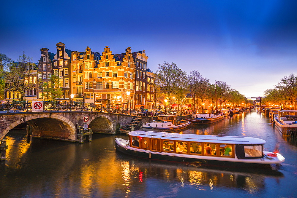 Canal scene with tour boat at dusk, Amsterdam, Netherlands, Europe