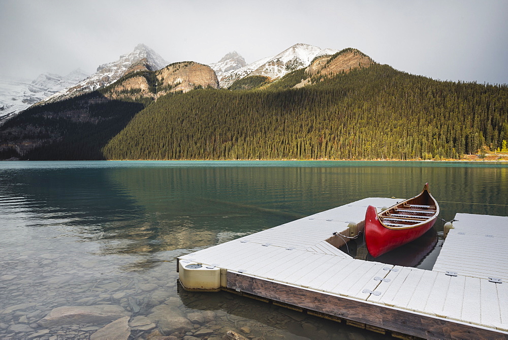 Red canoe and dock in Lake Louise with snow-covered mountains, Banff National Park, UNESCO World Heritage Site, Alberta, The Rockies, Canada, North America