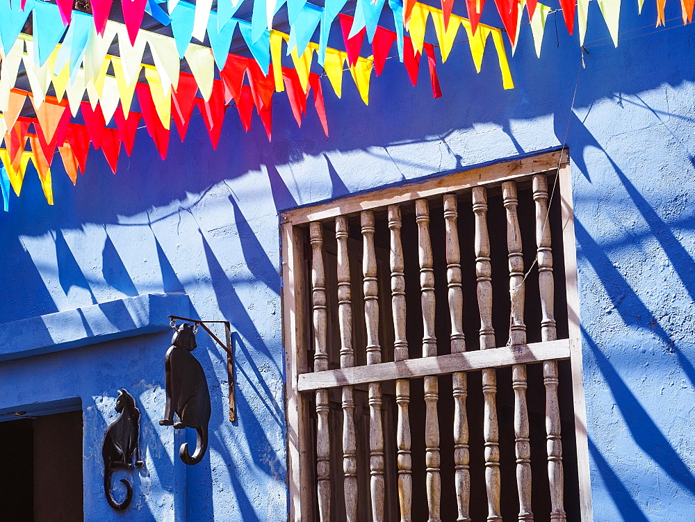 Colorful flags and a blue building with a cat sign, Getsemani barrio, Cartagena, Colombia, South America