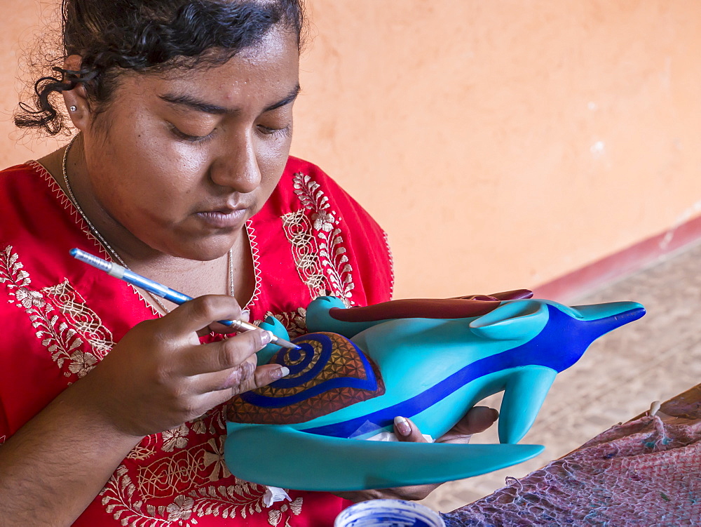 Woman painting a colorful carved wooden figure (alebrije) of a wolf, Oaxaca area, Mexico, North America