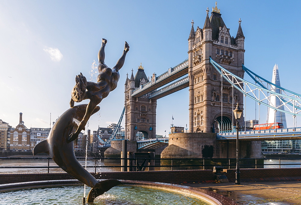 Juxtaposition of David Wynne's Girl With A Dolphin statue near Tower Bridge and Victorian engineering on the River Thames, London, England, United Kingdom, Europe