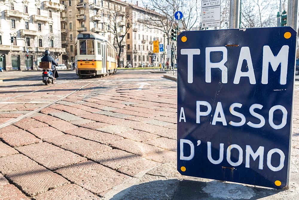 An old sign in Italian that says Trams go to Duomo, with a traditional Milanese tram in the background, Milan, Lombardy, Italy, Europe