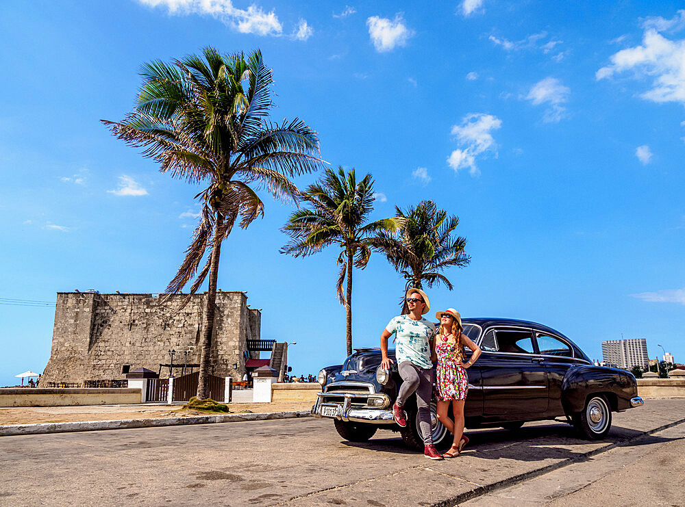 Cuban Couple with Vintage Chevrolet Car, Tower of la Chorrera in the background, Havana, La Habana Province, Cuba, West Indies, Caribbean, Central America