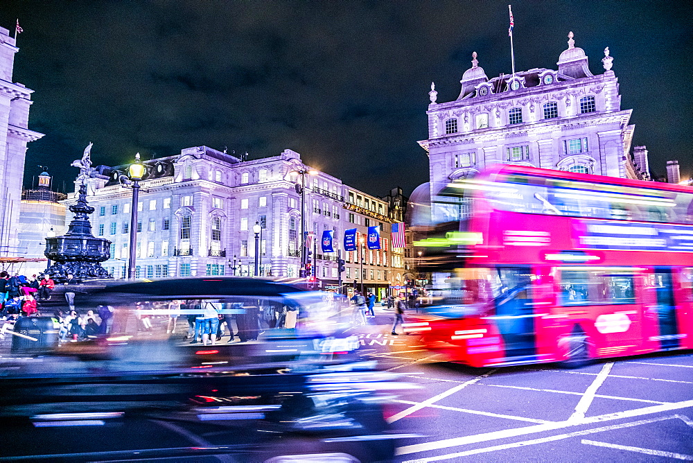 A bus and taxi zoom round Piccadilly Circus, London, England, United Kingdom, Europe