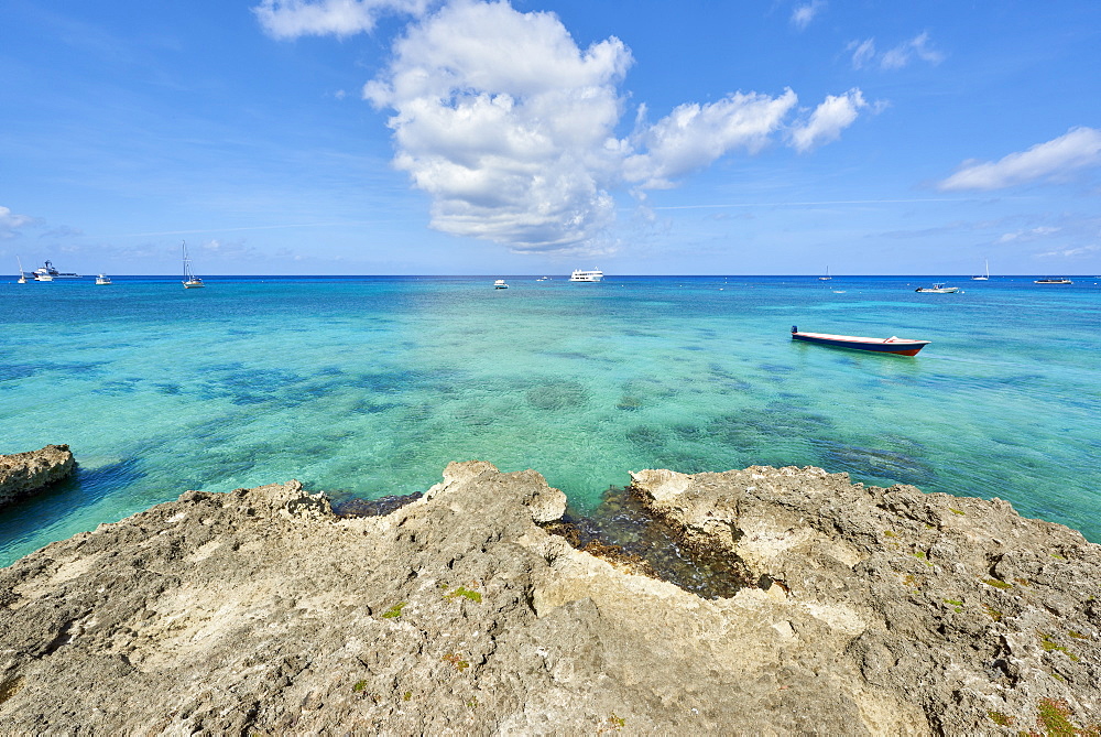 Rocky coastline in Cayman Islands with fishing boat in the transparent blue water, Cayman Islands, West Indies, Caribbean, Central America