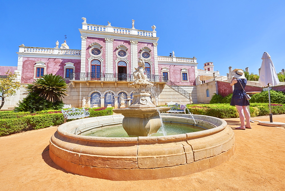 A tourist takes a photo at the entrance of Estoi Palace, in the Algarve, Portugal, Europe