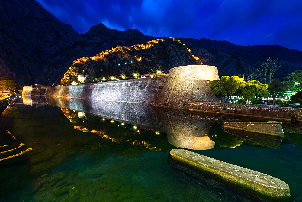 Part of Kotor's old town wall and lit fortress ramparts reflected during the evening blue hour, Montenegro, Europe