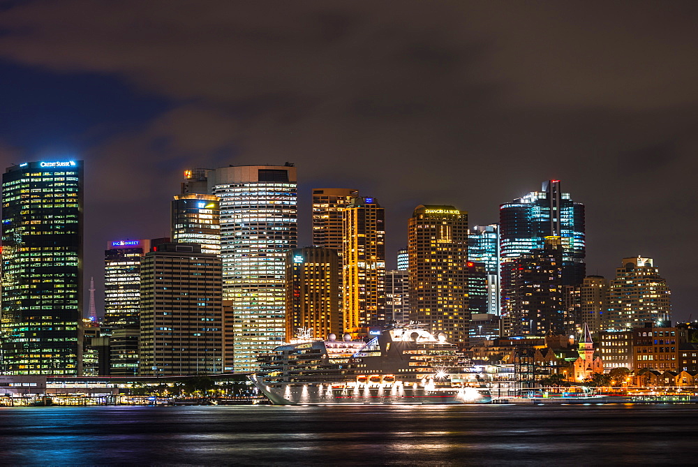 Large cruise ship docked at International Terminal in Sydney harbour after dark with city skyline, Sydney, New South Wales, Australia, Pacific