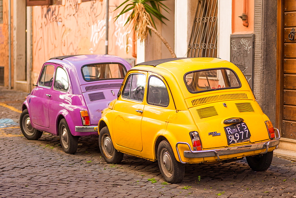 Two vintage Fiat 500s with Roma number plates parked in colourful backstreet of Trastevere, Lazio, Italy, Europe