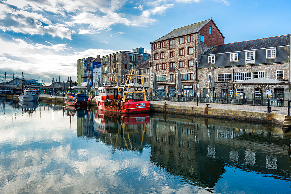 Fishing boats moored at Sutton harbour, with shops and cafes on the quayside, The Barbican, Plymouth, Devon, England, United Kingdom, Europe