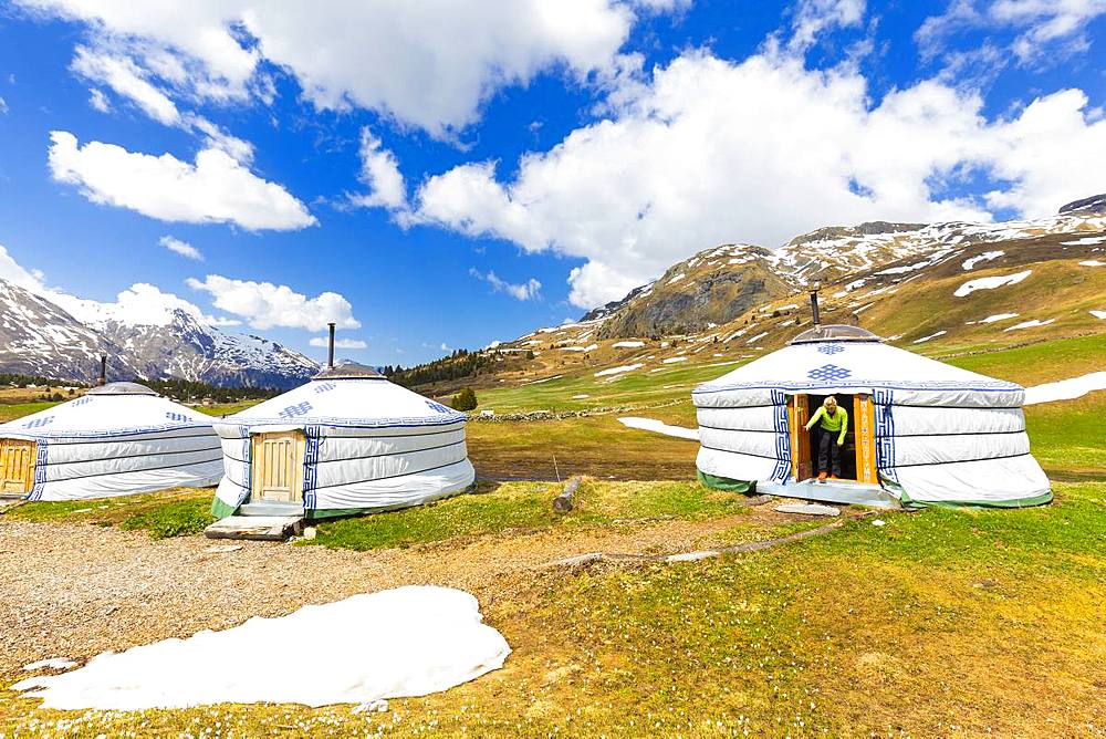 A girl comes out of a Mongolian tent at Alp Flix, Sur, Parc Ela, Region of Albula, Canton of Graubunden, Switzerland, Europe