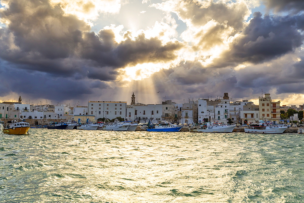 Old town illuminated by sun rays that filters between clouds, Monopoli, Apulia, Italy, Europe