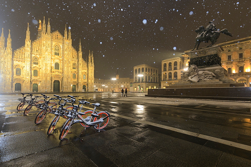 Parked bicycles in Piazza Duomo during a night snowfall, Milan, Lombardy, Northern Italy, Italy, Europe