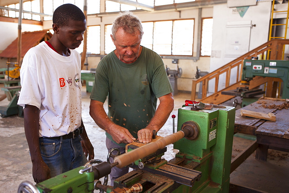 A VSO volunteer teaching how to use a lathe during a VSO woodwork vocational skills training workshop, Tanzania, East Africa, Africa