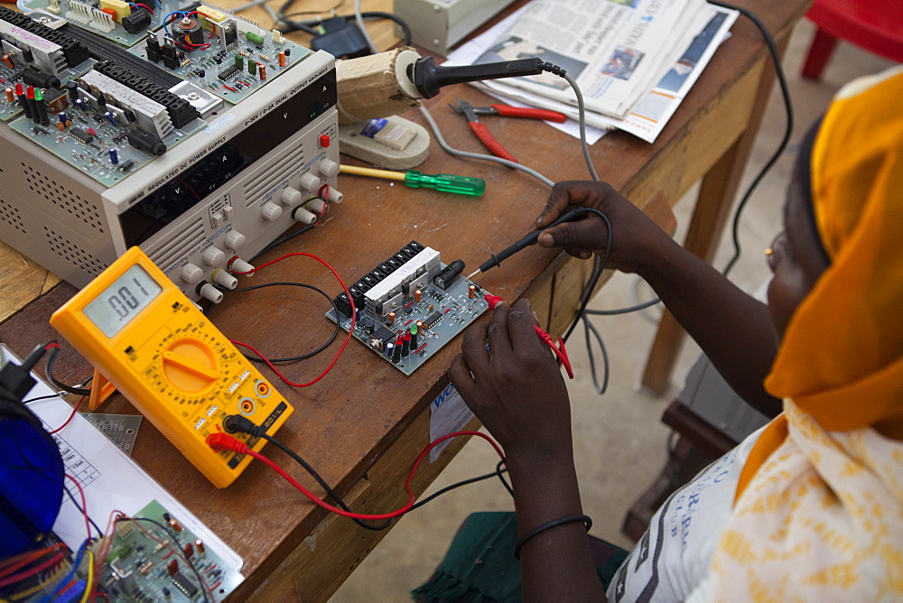 A woman, known as a Solar Mama, fixes a solar circuit board, Tanzania, East Africa, Africa