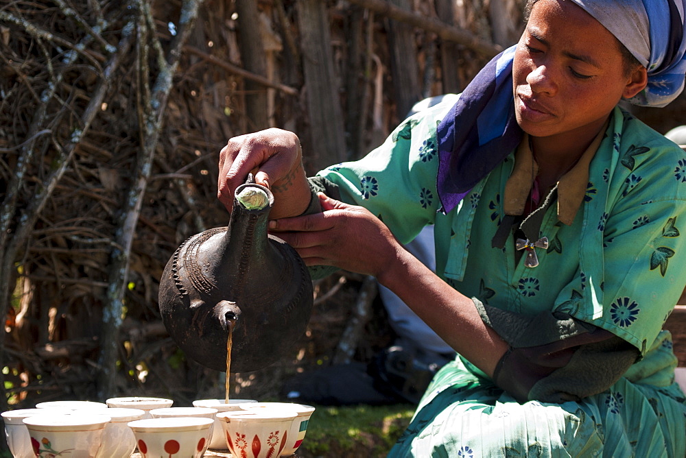 A woman pouring coffee from a traditional Ethiopian coffee pot, Ethiopia, Africa