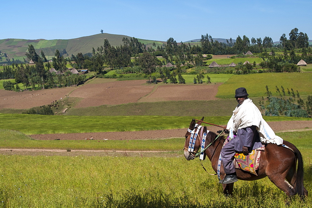 A man on horseback with a beautiful view of the rolling hills of rural Ethiopia, Africa