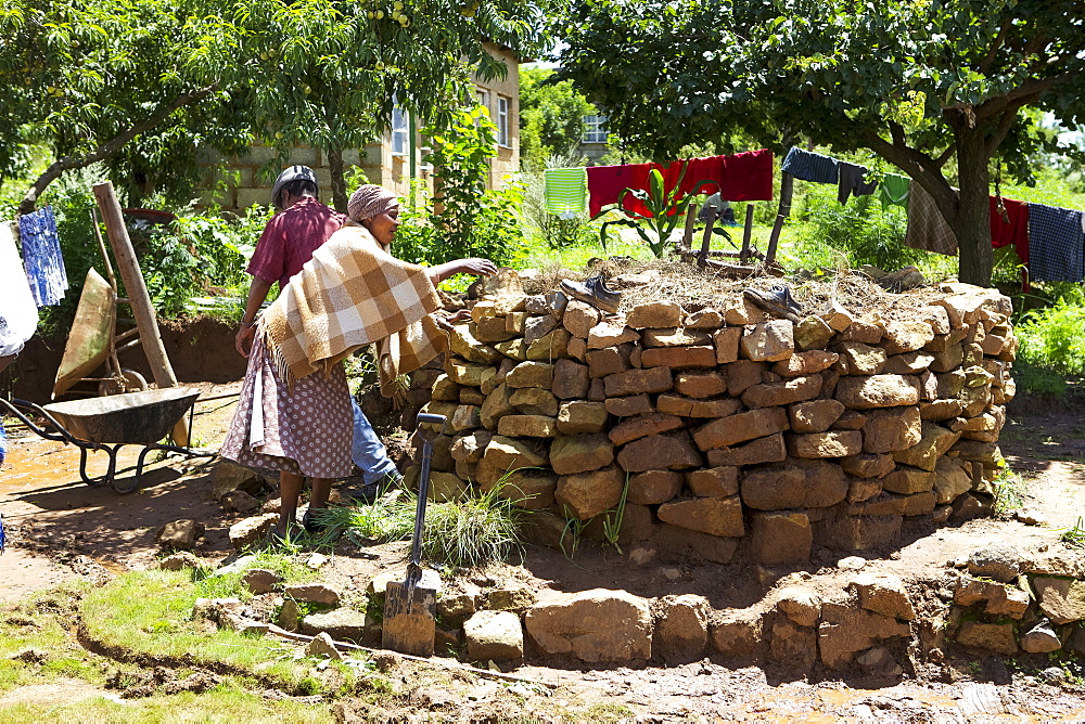 A couple help each other to build a keyhole garden, Lesotho, Africa