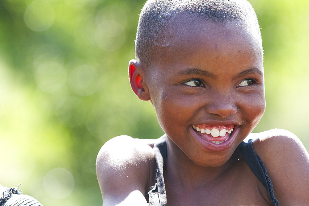 A young girl smiling and looking off to the right, Lesotho, Africa