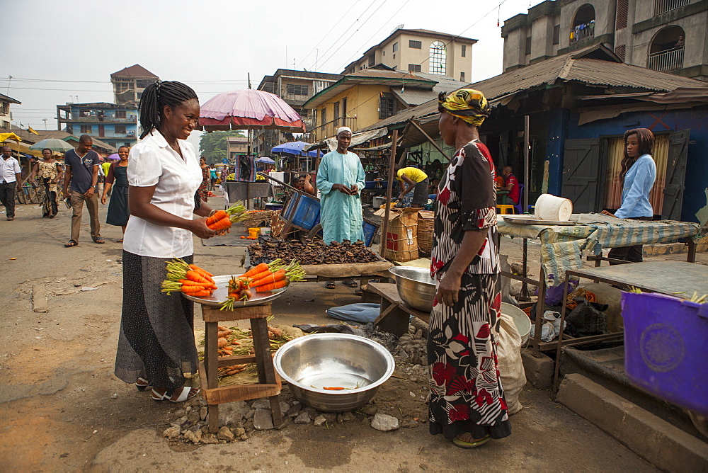 A woman buying carrots in the market in Nigeria, West Africa, Africa