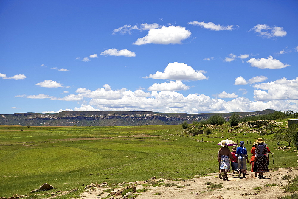 A group of woman walking through the rural countryside of Lesotho under a big blue sky, Lesotho, Africa