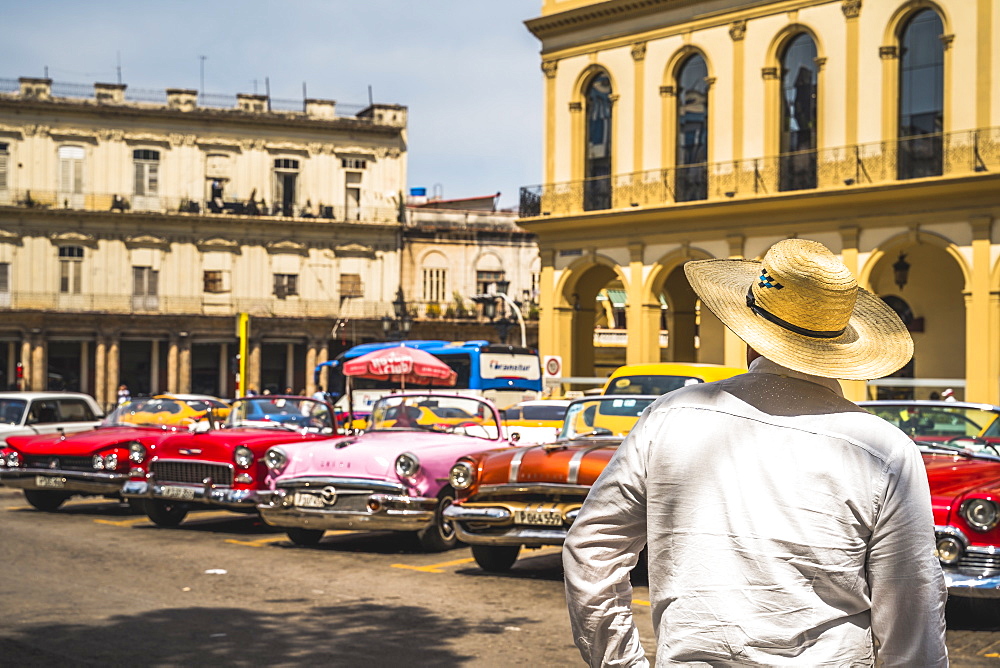 Cuban man overlooking colourful old American taxi cars parked in Havana, La Habana, Cuba, West Indies, Caribbean Central America