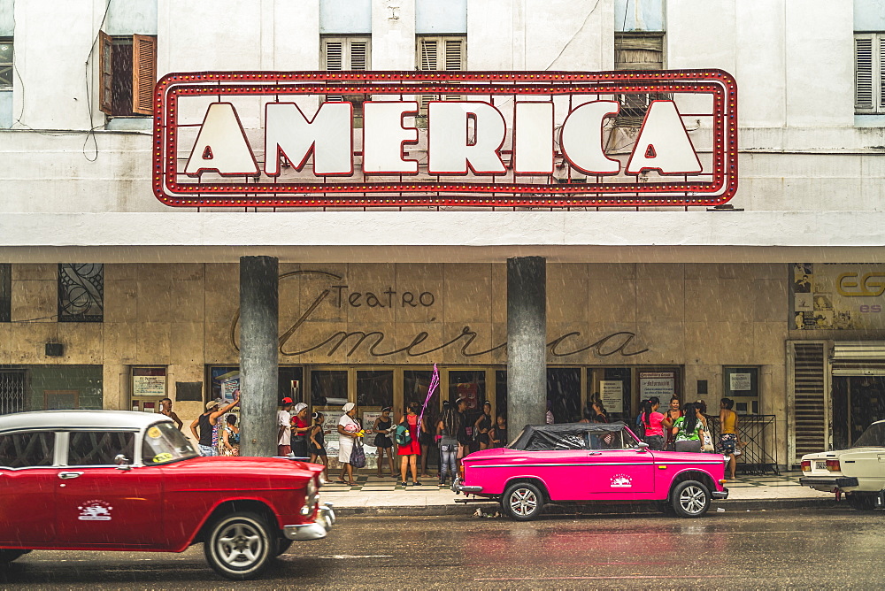 Pink and red vintage cars outside Teatro America in rain, La Habana (Havana), Cuba, West Indies, Caribbean, Central America