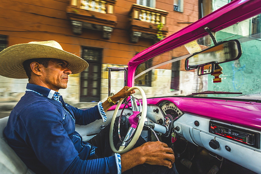 Local classic car driver at sunset in La Habana, Havana, Cuba, West Indies, Caribbean, Central America