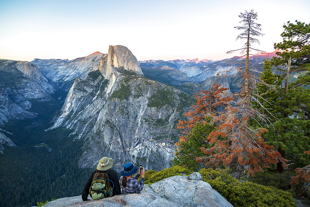 A couple takes a break at Glacier Point to look at Half Dome in Yosemite National Park, UNESCO World Heritage Site, California, United States of America, North America