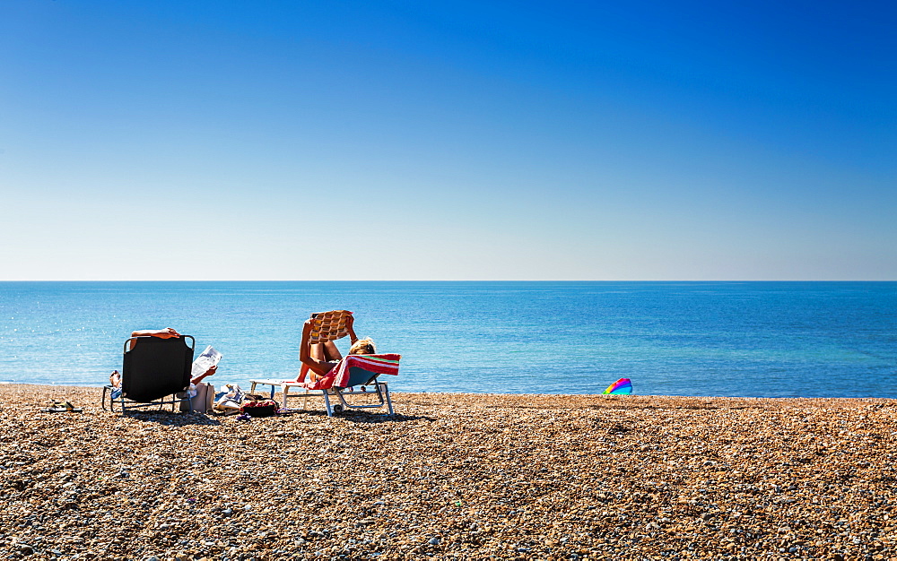 People relaxing on deckchairs on the beach, Brighton, East Sussex, England, United Kingdom, Europe