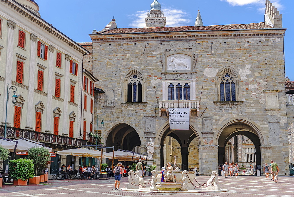 Old Town Palace (Palazzo della Ragione) on Piazza Vecchia with fountain and crowd in Citta Alta, Bergamo, Lombardy, Italy, Europe