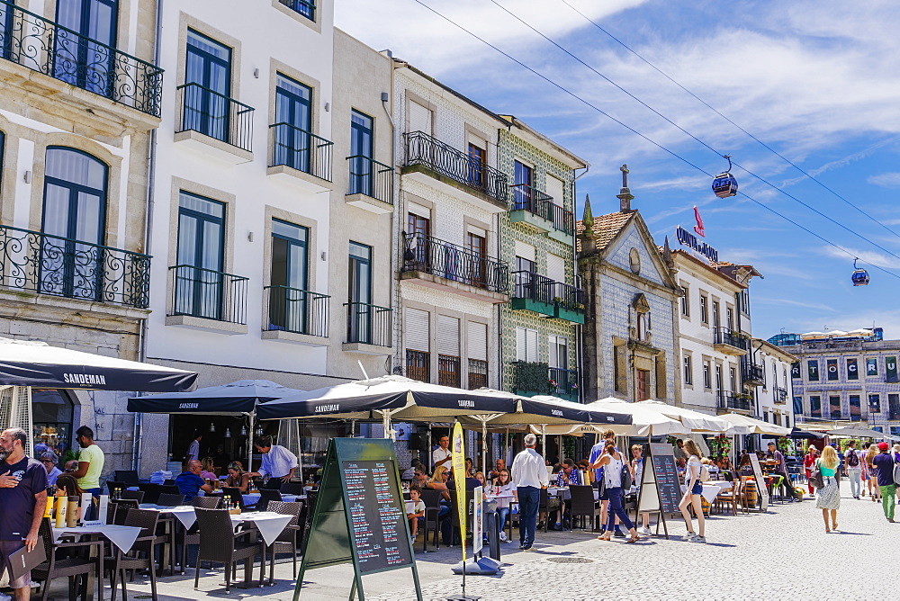 Day view of food shops with outdoor seats by Douro River waterfront and buildings, Vila Nova de Gaia, Porto, Portugal, Europe