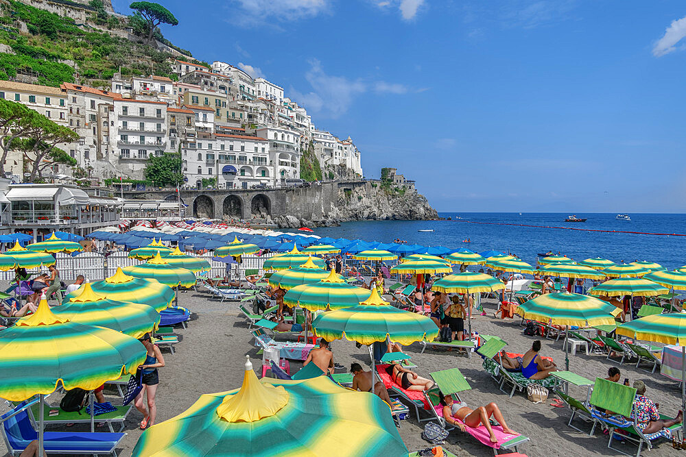 Beach view with bathers and colorful umbrellas before low rise buildings, Amalfi Town, Costiera Amalfitana, UNESCO World Heritage Site, Campania, Italy, Europe