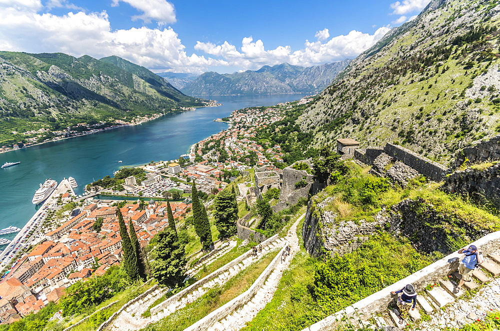 Hikers walking the old city walls during the daytime above the Bay of Kotor, UNESCO World Heritage Site, Montenegro, Europe