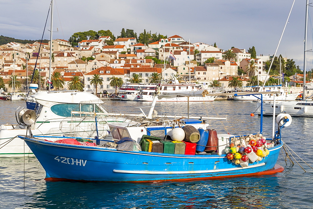 Colorful boat anchoring in the port of Hvar Town with view to the old town in the background, Hvar, Croatia, Europe